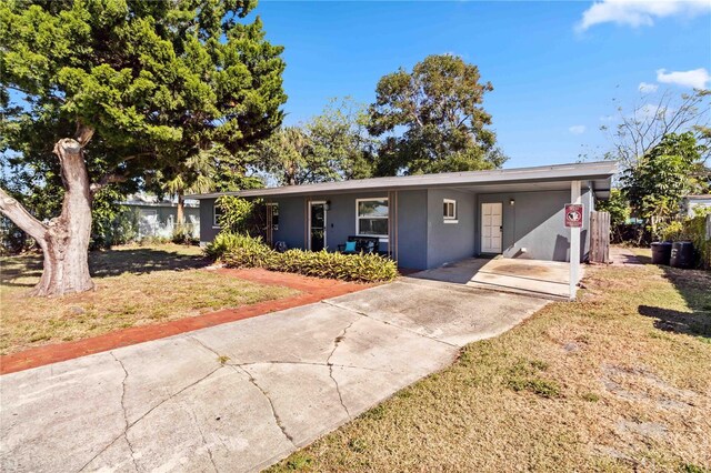 ranch-style house featuring a front lawn and a carport