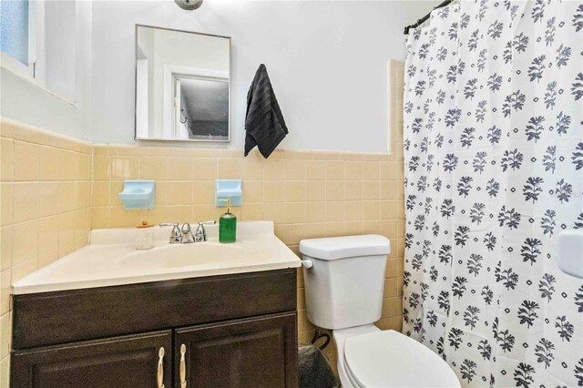 bathroom with walk in shower, vanity, tile walls, and toilet