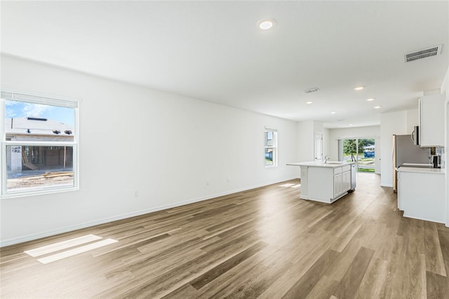 unfurnished living room with sink and light hardwood / wood-style floors