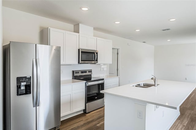 kitchen with appliances with stainless steel finishes, sink, white cabinetry, and an island with sink