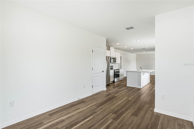 unfurnished living room featuring sink and dark wood-type flooring