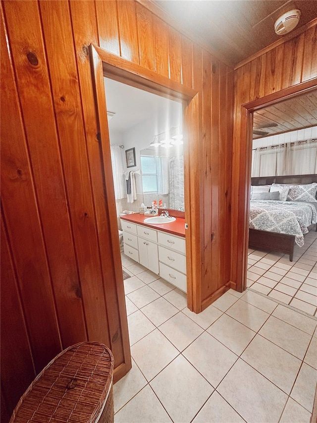 bathroom with tile patterned flooring, vanity, and wood walls