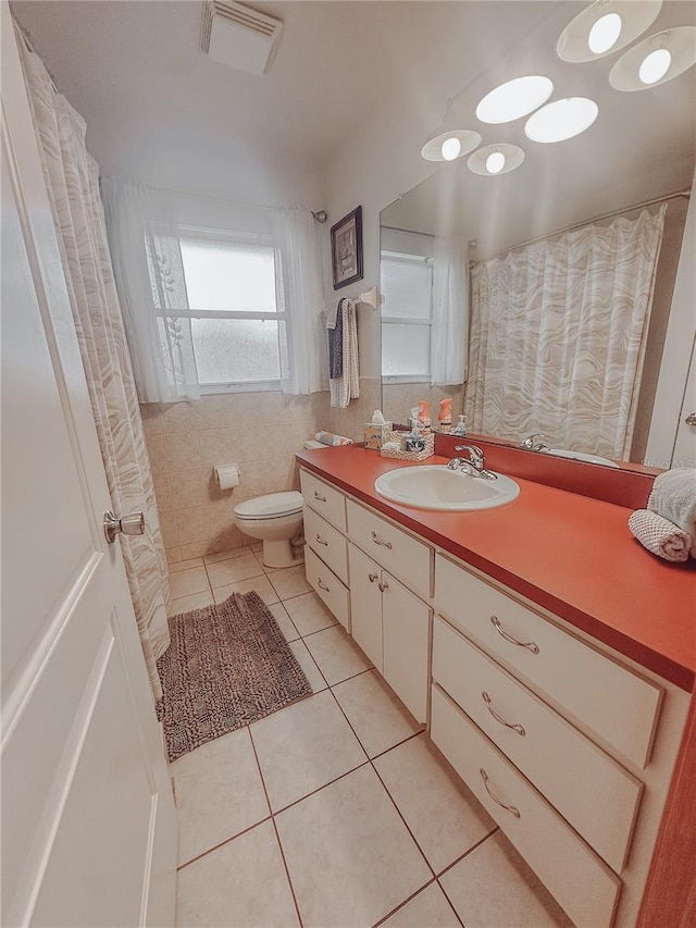 bathroom featuring tile patterned flooring, vanity, toilet, and tile walls