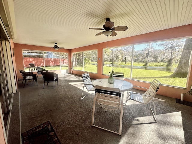 sunroom / solarium with ceiling fan, a healthy amount of sunlight, and a water view