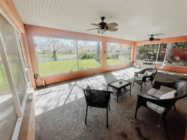 sunroom / solarium featuring a water view and ceiling fan