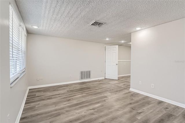 spare room featuring wood-type flooring and a textured ceiling