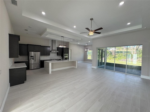 unfurnished living room featuring ceiling fan, a tray ceiling, and light hardwood / wood-style flooring