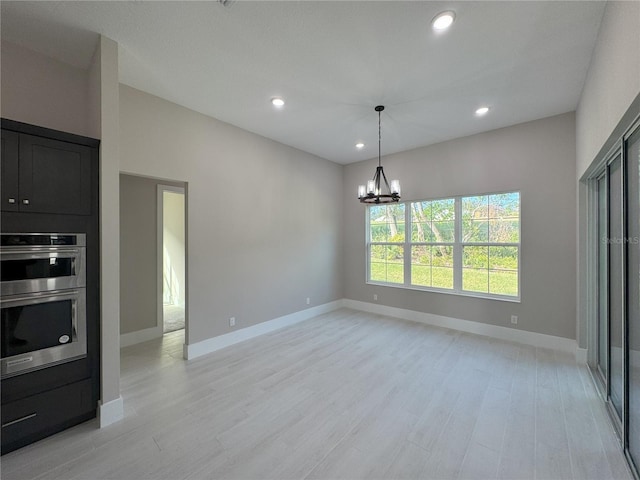 kitchen with a notable chandelier, light hardwood / wood-style floors, stainless steel double oven, and hanging light fixtures