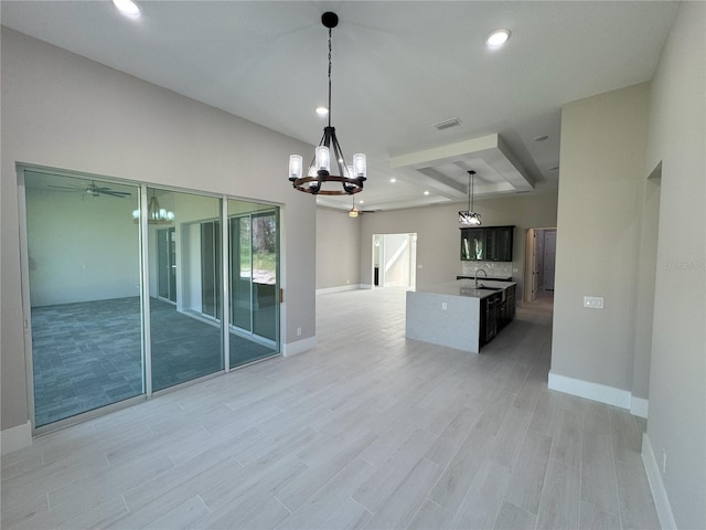 kitchen with ceiling fan with notable chandelier, light hardwood / wood-style floors, hanging light fixtures, and a center island with sink