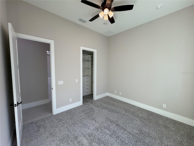 unfurnished bedroom with carpet flooring, ceiling fan, a walk in closet, and a closet