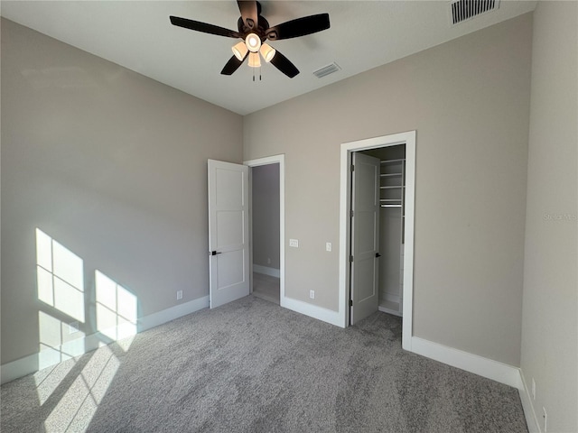 unfurnished bedroom with ceiling fan, light colored carpet, a spacious closet, and a closet