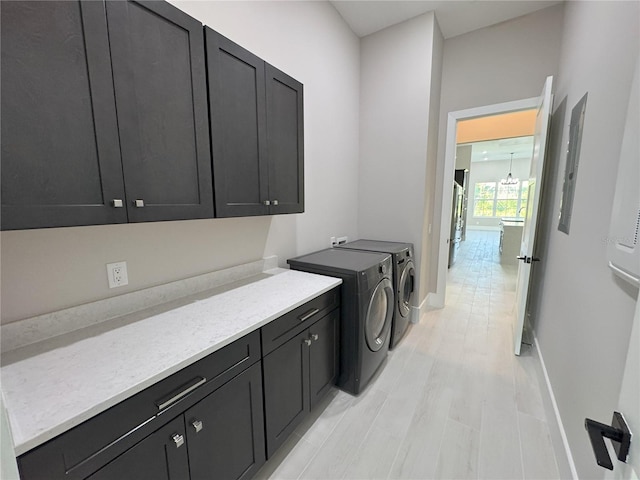 laundry area with light hardwood / wood-style floors, cabinets, independent washer and dryer, and an inviting chandelier