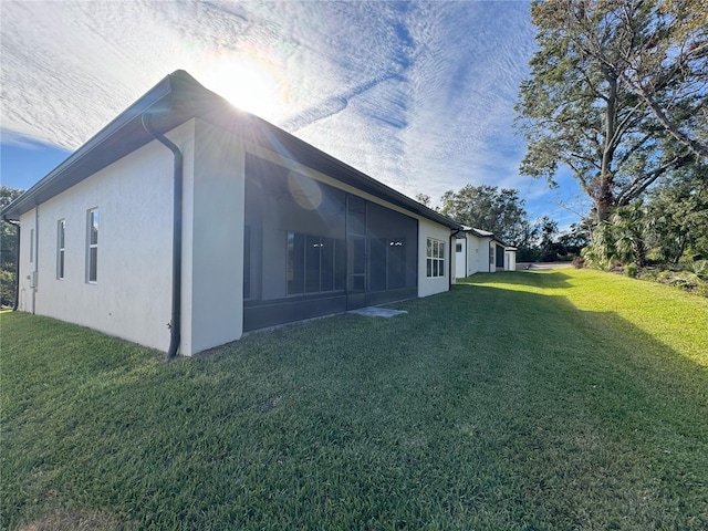 view of side of home with a sunroom and a yard