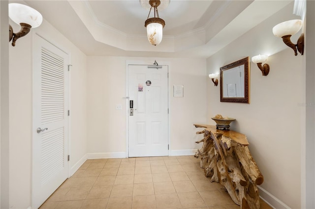 entrance foyer featuring light tile patterned flooring, a raised ceiling, and ornamental molding