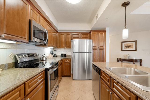 kitchen featuring a textured ceiling, decorative light fixtures, decorative backsplash, light tile patterned flooring, and appliances with stainless steel finishes