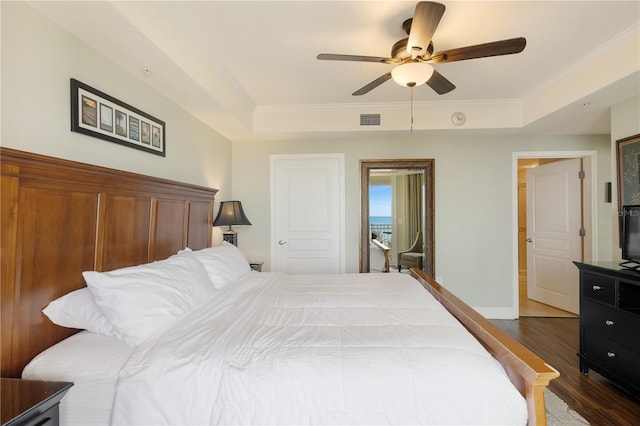 bedroom with a raised ceiling, ceiling fan, dark wood-type flooring, and ornamental molding