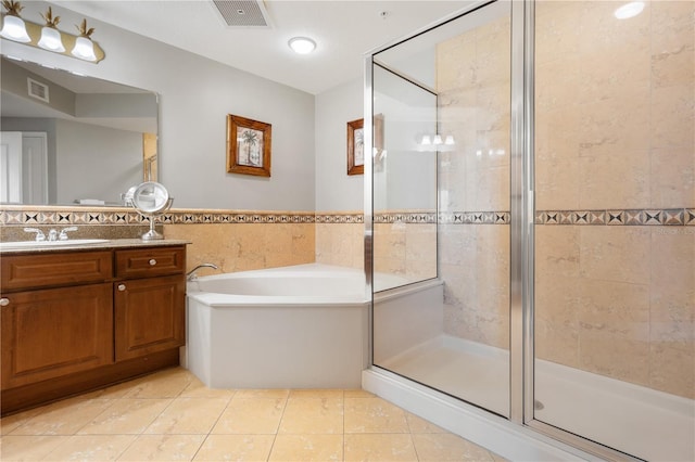 bathroom with plus walk in shower, vanity, tile patterned floors, and tile walls