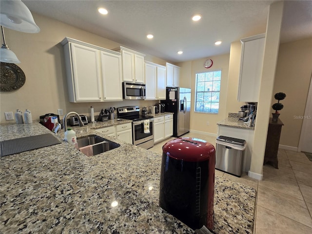 kitchen featuring appliances with stainless steel finishes, light stone counters, sink, white cabinets, and light tile patterned flooring