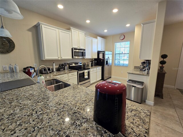 9037 Shadow Mountain St, Davenport, FL 33896 - kitchen with appliances with stainless steel finishes, light stone counters, white cabinetry, recessed lighting, and light tile patterned floors