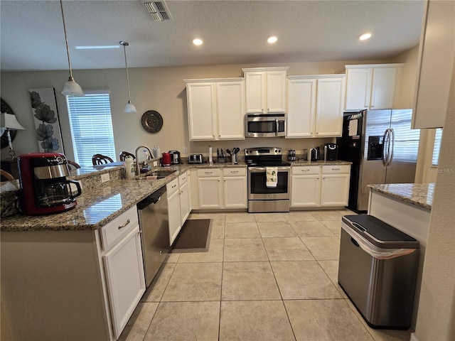 kitchen featuring pendant lighting, kitchen peninsula, white cabinetry, and stainless steel appliances