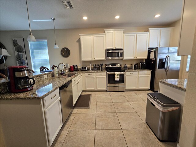 9037 Shadow Mountain St, Davenport, FL 33896 - kitchen featuring stainless steel appliances, a peninsula, white cabinets, light stone countertops, and recessed lighting