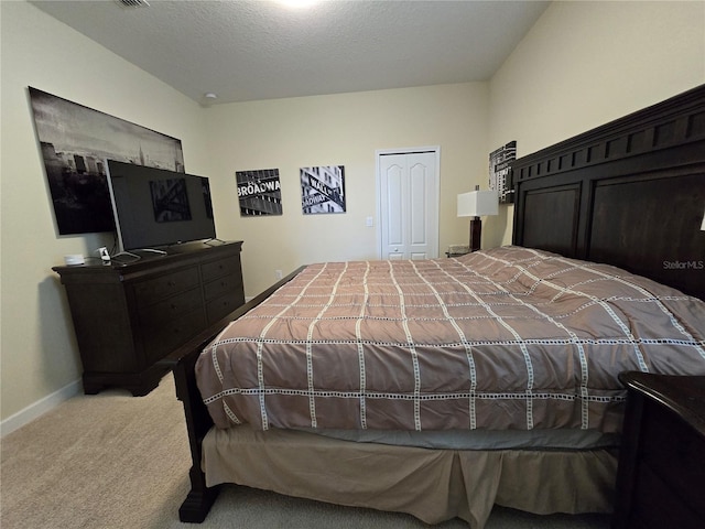 bedroom featuring light colored carpet, a textured ceiling, and a closet