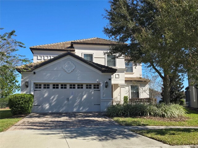 9037 Shadow Mountain St, Davenport, FL 33896 - mediterranean / spanish-style home with decorative driveway, an attached garage, a tiled roof, and stucco siding