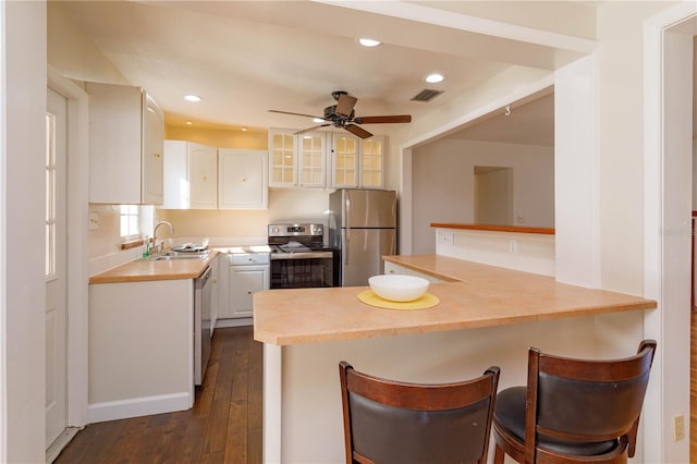 kitchen featuring appliances with stainless steel finishes, dark hardwood / wood-style flooring, sink, white cabinetry, and a breakfast bar area