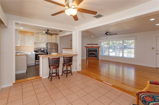 kitchen with white cabinets, appliances with stainless steel finishes, light hardwood / wood-style flooring, and a kitchen breakfast bar