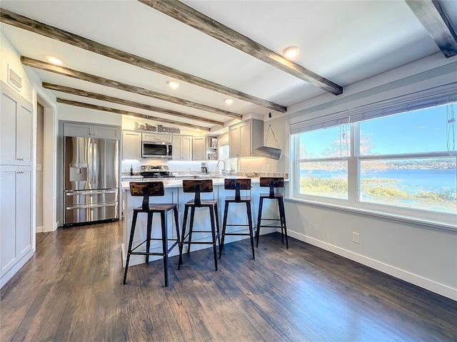 kitchen with kitchen peninsula, appliances with stainless steel finishes, gray cabinets, dark hardwood / wood-style floors, and a breakfast bar area