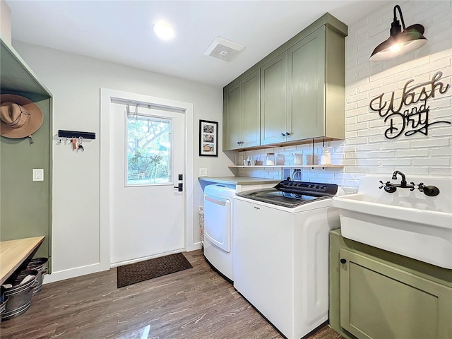 washroom with independent washer and dryer, cabinets, wood-type flooring, and sink