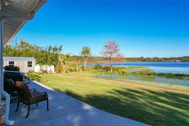 view of yard featuring a patio area, a water view, and an outdoor structure