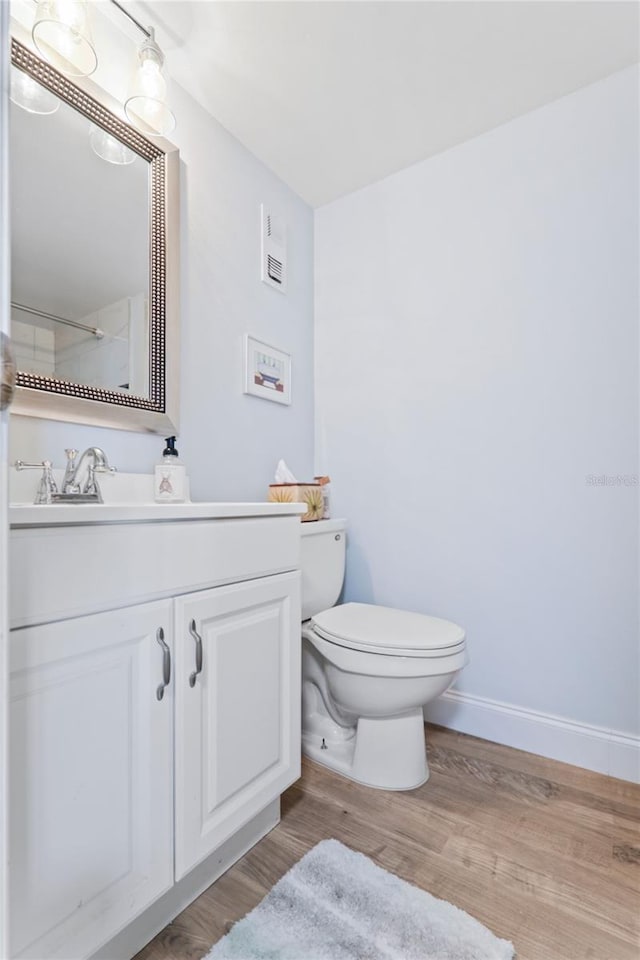 bathroom with hardwood / wood-style floors, vanity, and toilet