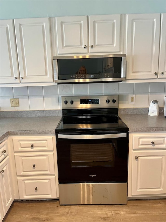 kitchen featuring tasteful backsplash, white cabinets, stainless steel appliances, and light hardwood / wood-style floors