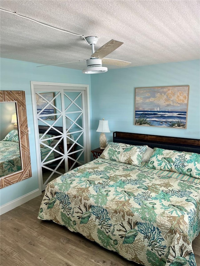 bedroom with wood-type flooring, a textured ceiling, and ceiling fan