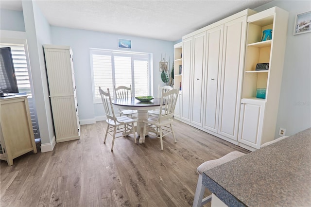 dining area with light hardwood / wood-style floors and a textured ceiling