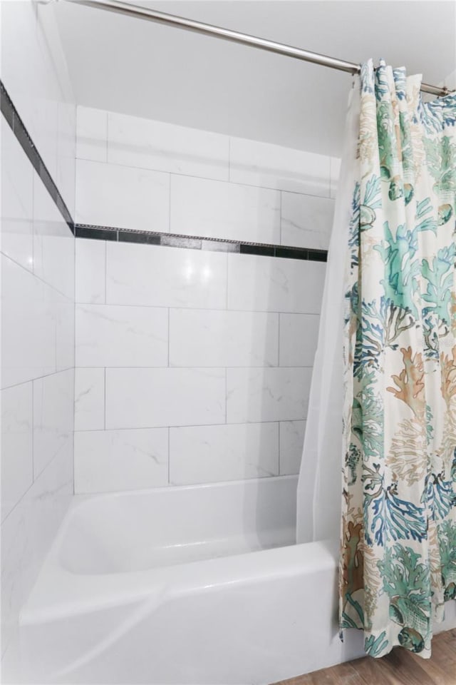 bathroom featuring hardwood / wood-style flooring and shower / bathtub combination with curtain