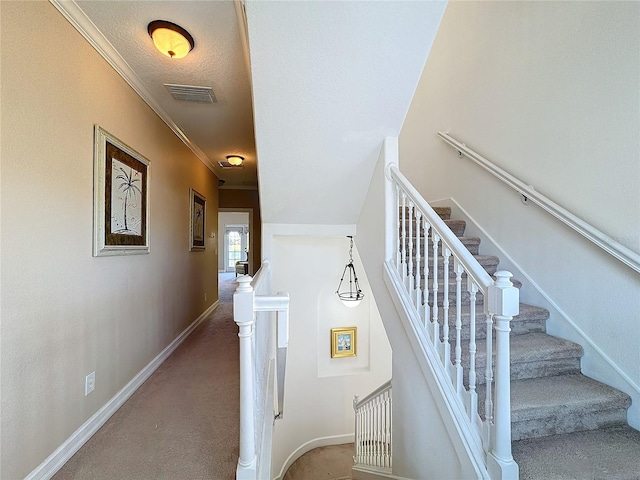 stairs with carpet, a textured ceiling, and ornamental molding