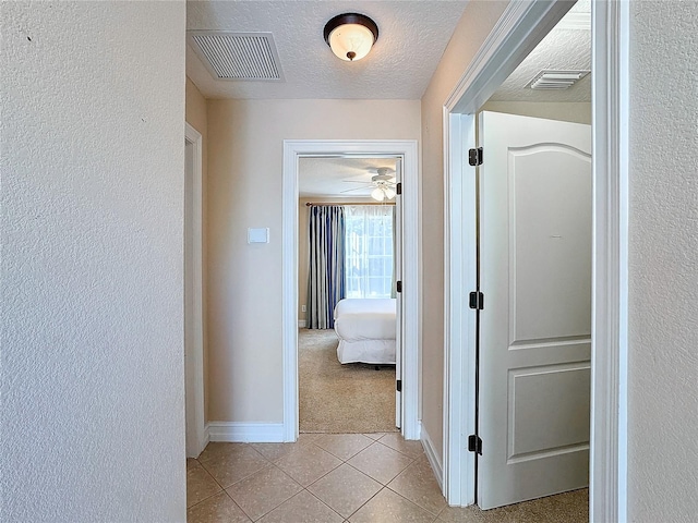 corridor featuring light colored carpet and a textured ceiling