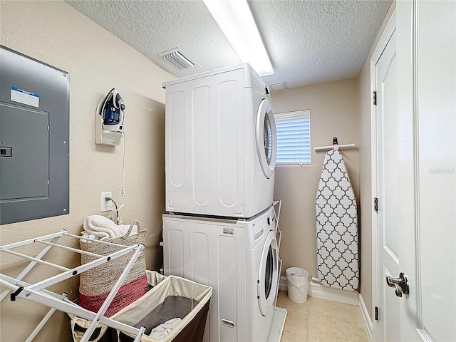 washroom featuring stacked washer / drying machine, light tile patterned floors, electric panel, and a textured ceiling