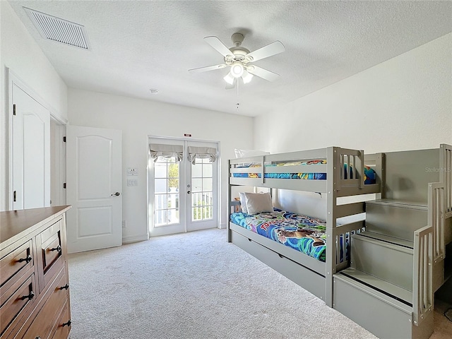 bedroom with light colored carpet, access to exterior, ceiling fan, a textured ceiling, and french doors