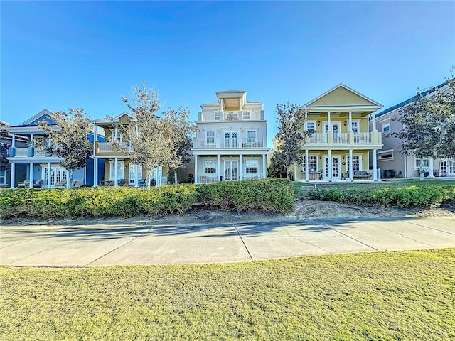 exterior space featuring french doors, a balcony, and a front lawn