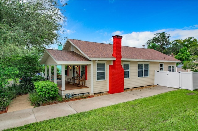 back of property with a lawn and a porch