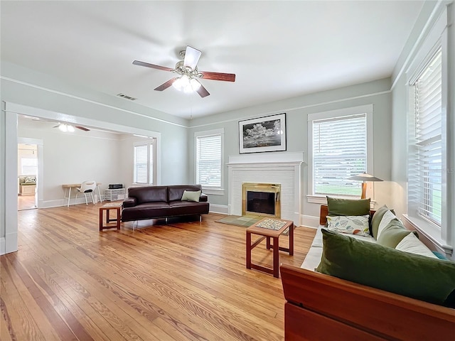 living room with ceiling fan, light hardwood / wood-style flooring, and a brick fireplace