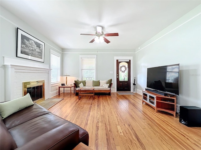 living room with ceiling fan, a fireplace, and light hardwood / wood-style floors