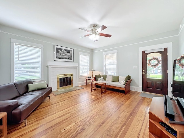 living room with a fireplace, a wealth of natural light, light hardwood / wood-style flooring, and ceiling fan