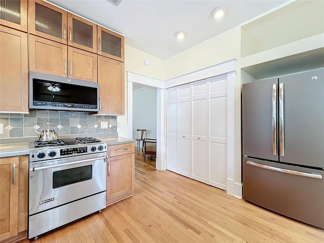 kitchen featuring decorative backsplash, appliances with stainless steel finishes, and light wood-type flooring