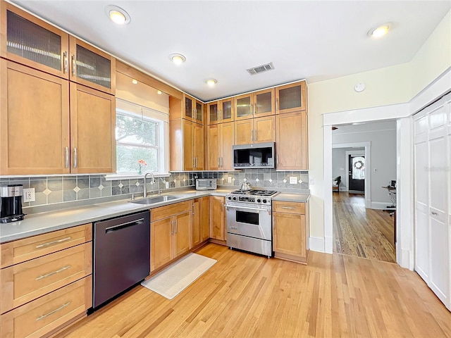 kitchen featuring decorative backsplash, light hardwood / wood-style floors, sink, and stainless steel appliances