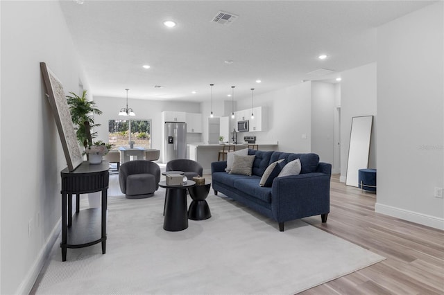 living room featuring an inviting chandelier and light hardwood / wood-style flooring