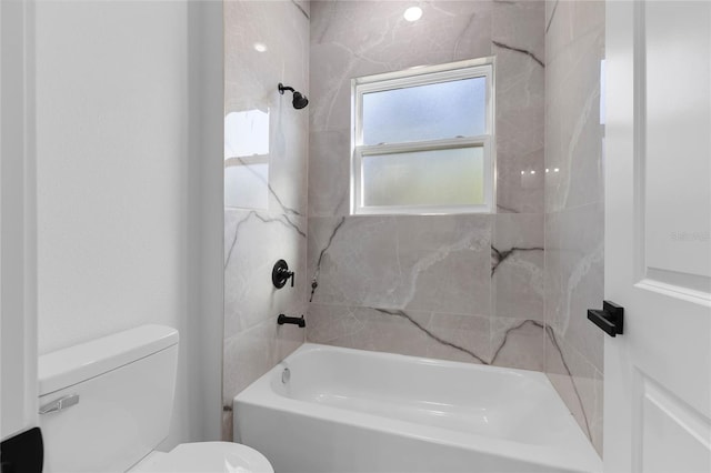 bathroom featuring toilet and tiled shower / bath